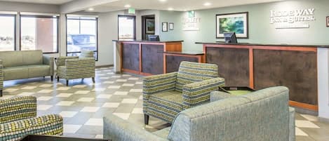 A hotel lobby with a reception desk, seating area, and framed artwork on the walls.