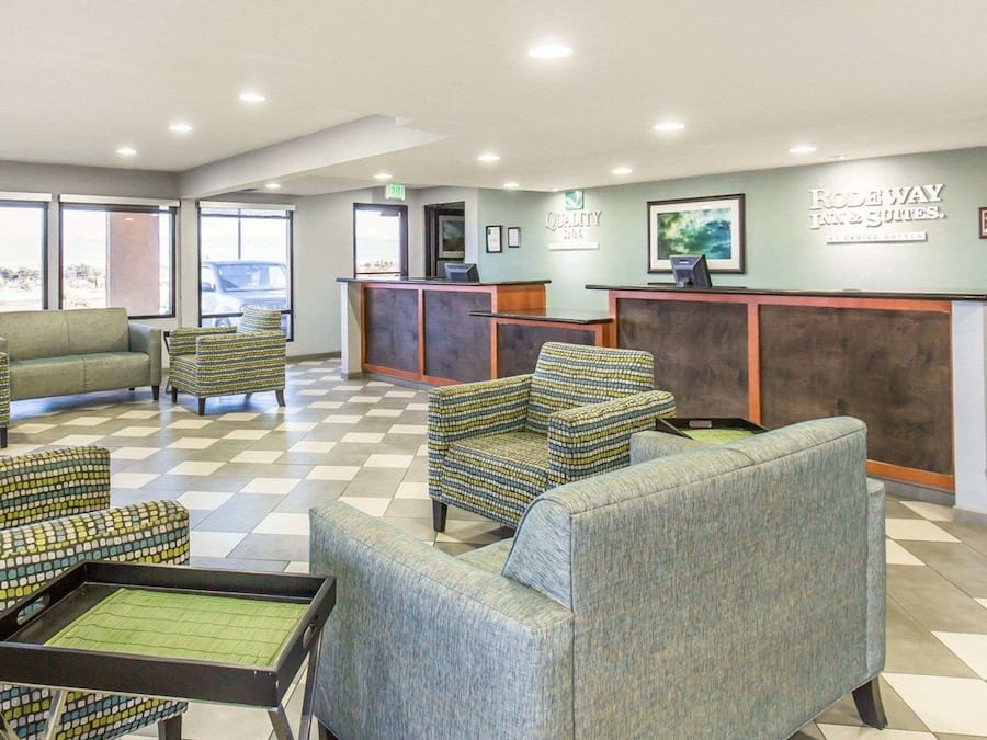 A hotel lobby with a reception desk, seating area, and framed artwork on the walls.