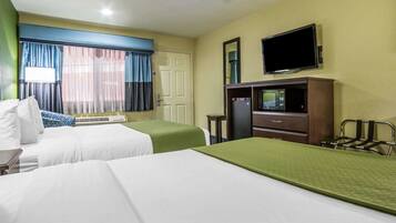 A hotel room with two beds, a television, a microwave, and a ceiling fan.