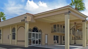 A two-story building with a beige facade, arched windows, and a covered entrance.