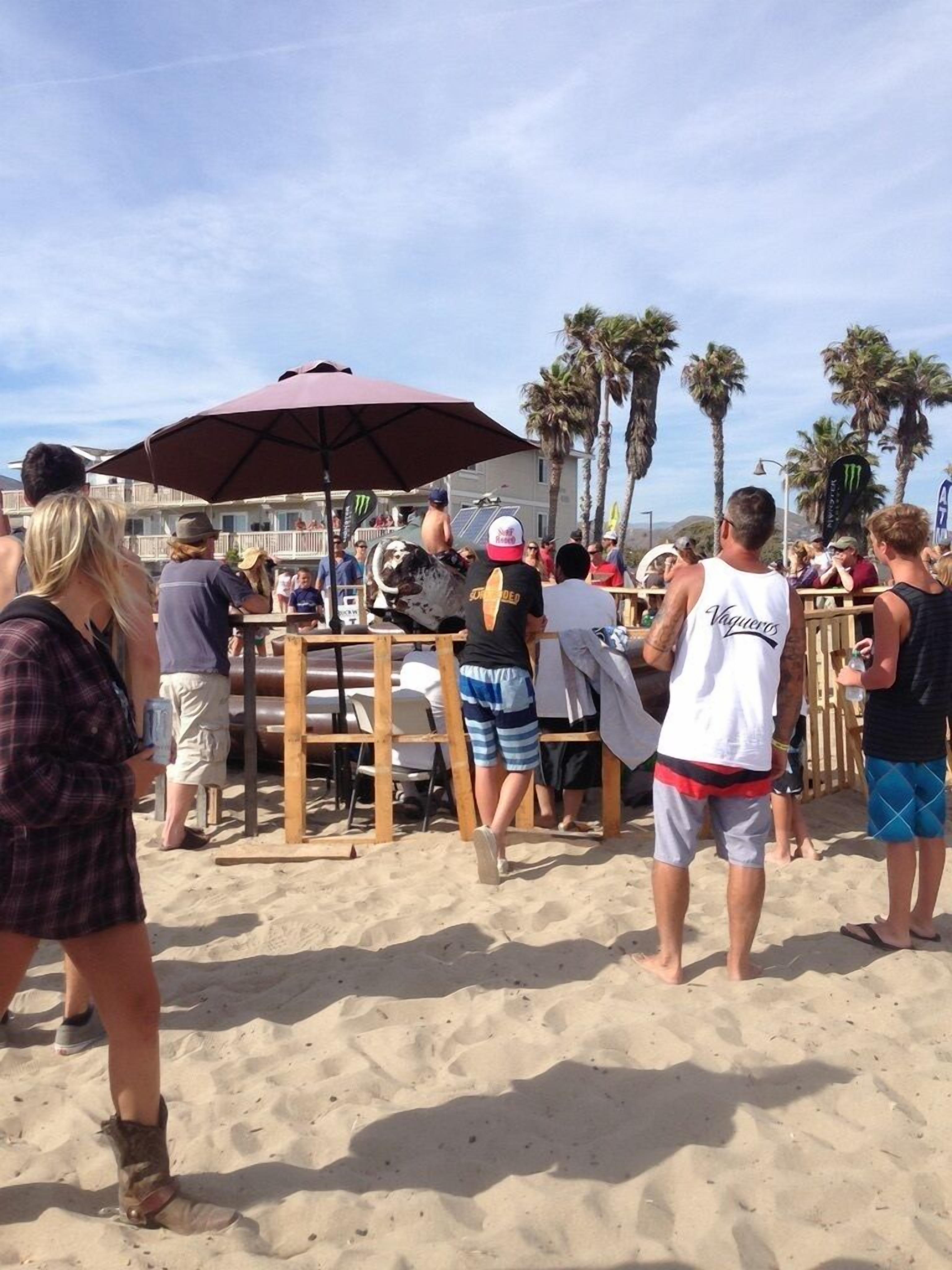 Un evento en la playa con vallas de madera y sombrillas.