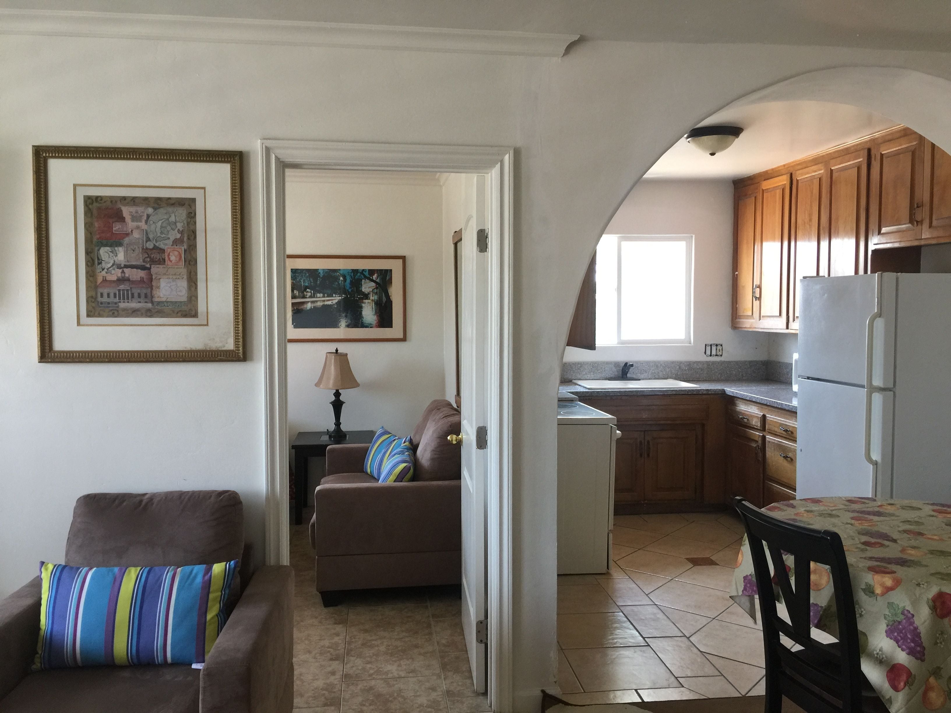 A compact living space with a kitchenette, a dining area, and a sofa with a colorful cushion.