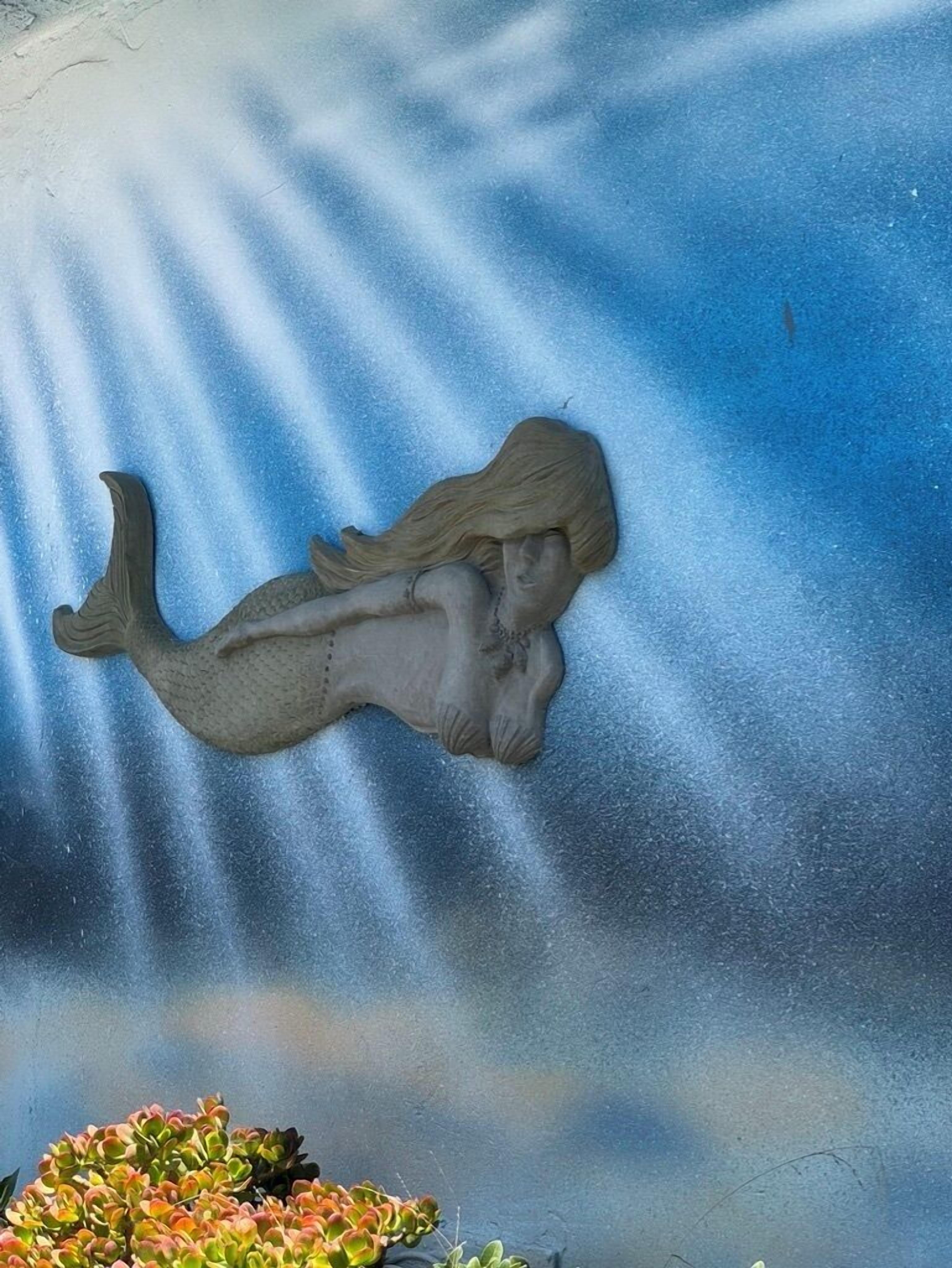 En skulptur av en sjöjungfru på en blå, strukturerad yta.