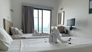 Une chambre d’hôtel avec deux lits, une télévision, un bureau et vue sur la mer.