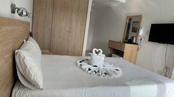 Quarto de hotel com cama, guarda-roupa de madeira, televisão e espelho.