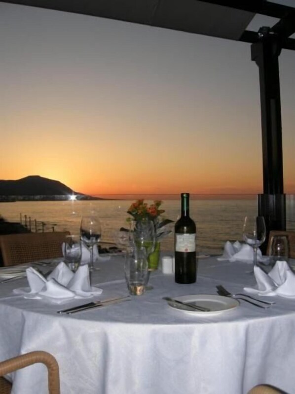 A table set for dining with a view of the sunset over the water.