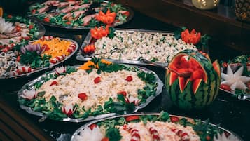 Una mesa de buffet con diversos platos, incluyendo ensaladas, arroz y carne, dispuestos en bandejas de metal.