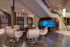 A lobby with a reception desk, two elevators, a large aquarium, and seating area with modern chairs. - Olymp II (Kolobrzeg)