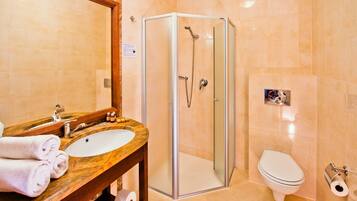 Un baño moderno con ducha de vidrio, lavamanos con encimera de mármol, inodoro y espejo.
