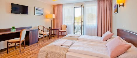 A hotel room with a bed, desk, chairs, and a TV.