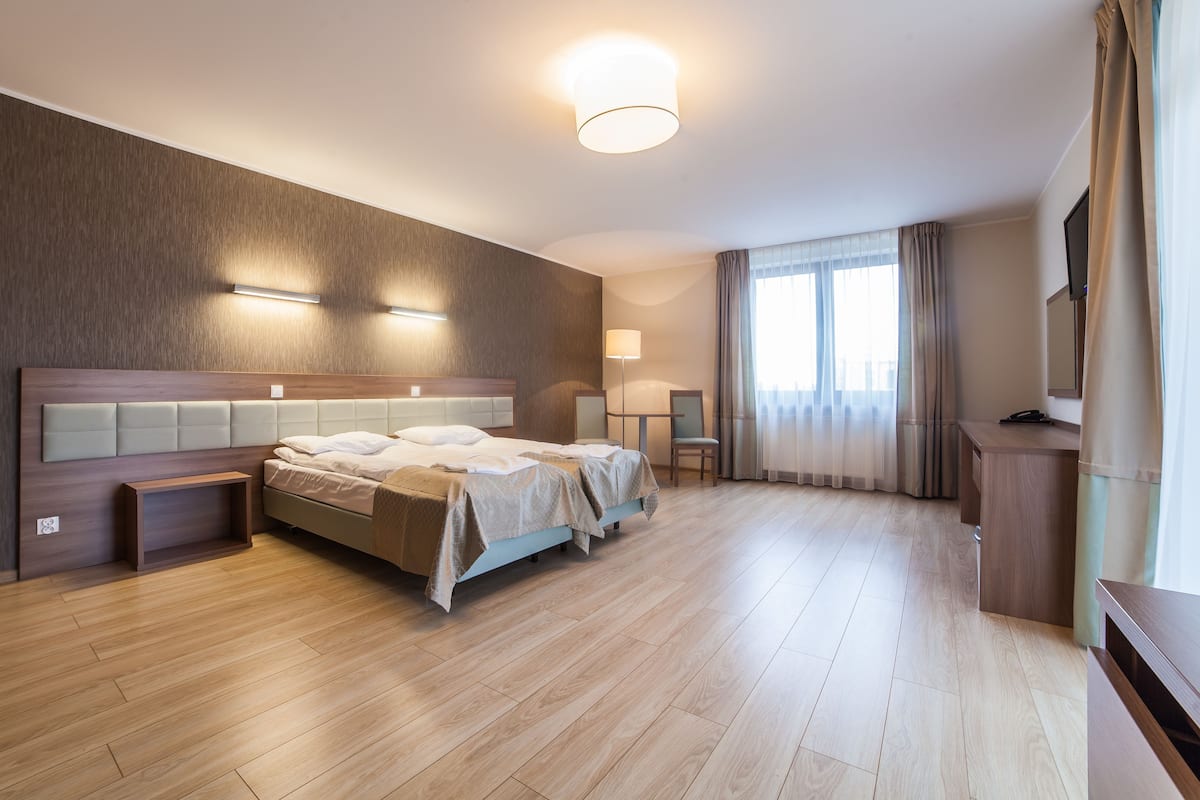 Ein modernes Hotelzimmer mit einem großen Bett, Nachttischen, einem Schreibtisch und einem Fernseher.
