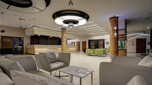 A modern lobby with sofas, a reception desk, and a bar area. - Olymp 3 (Kolobrzeg)