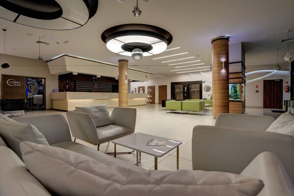 A modern lobby with sofas, a reception desk, and a bar area.