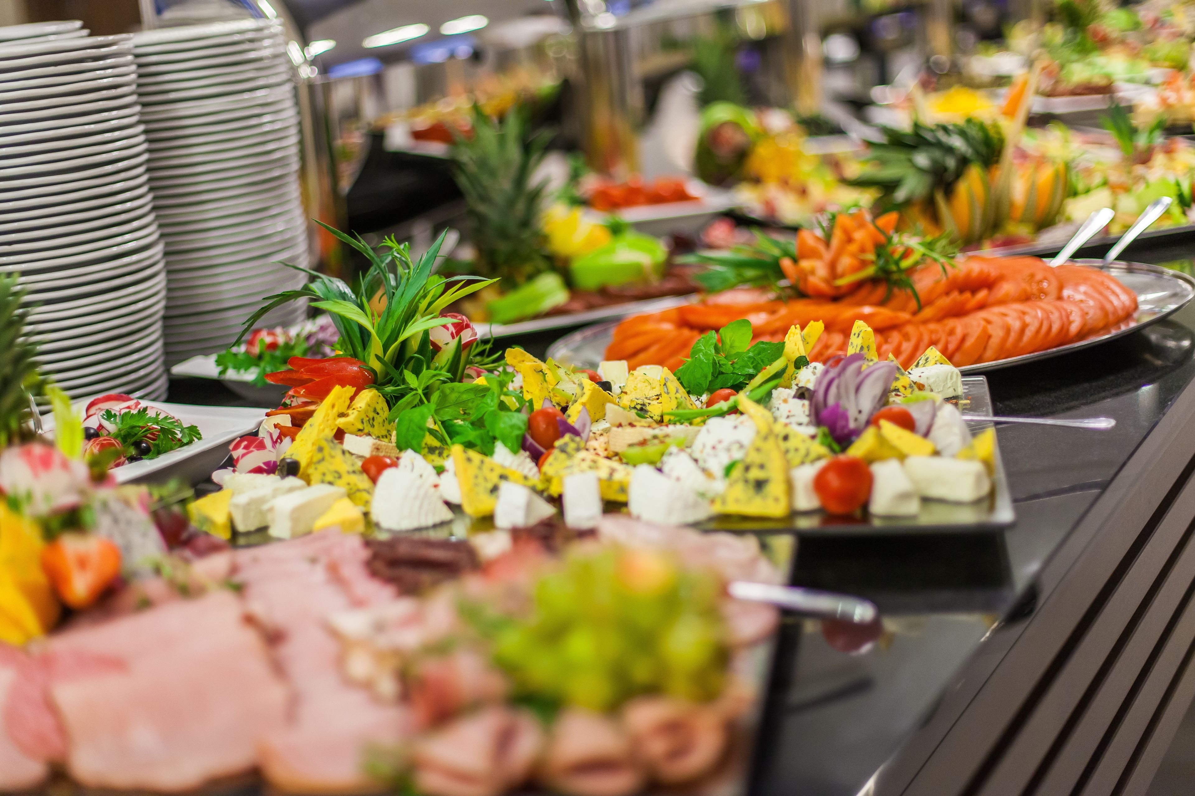 A buffet with various food items including fruits, vegetables, and cheeses.