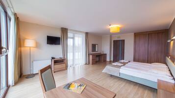 Habitación de hotel con cama, escritorio, silla, lámpara, televisor y vistas al exterior.