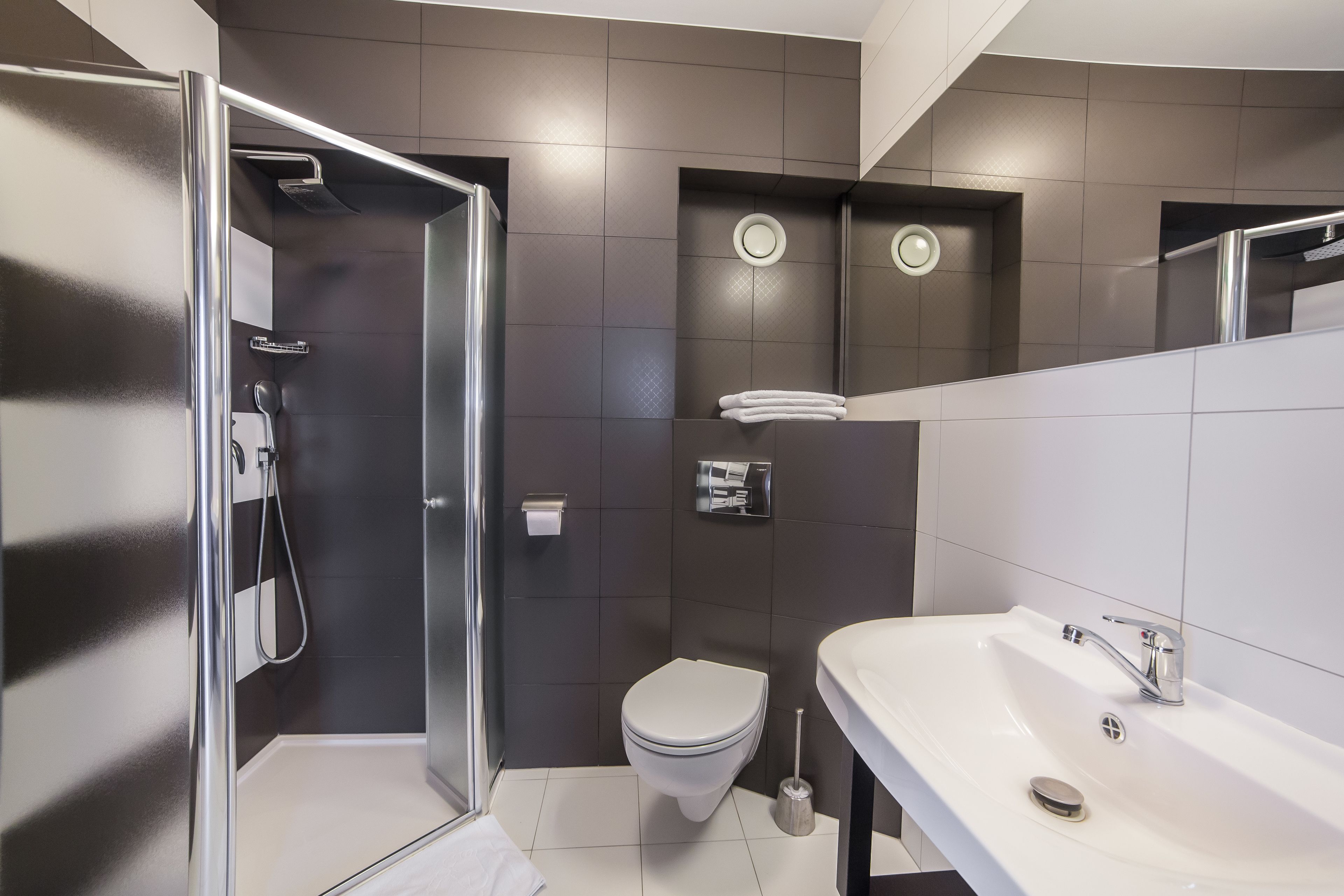 A modern bathroom with a shower, toilet, and sink.