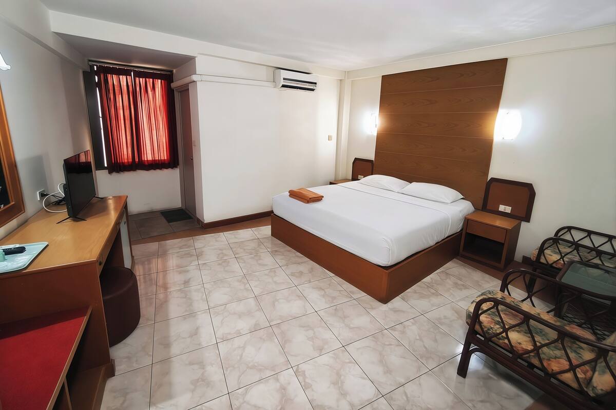 A hotel room with a bed, a desk, a chair, and a TV.