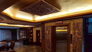 A lobby with a wooden floor, a reception desk, and an elevator with ornate carvings. - Dream Hotel Pattaya (Pattaya)