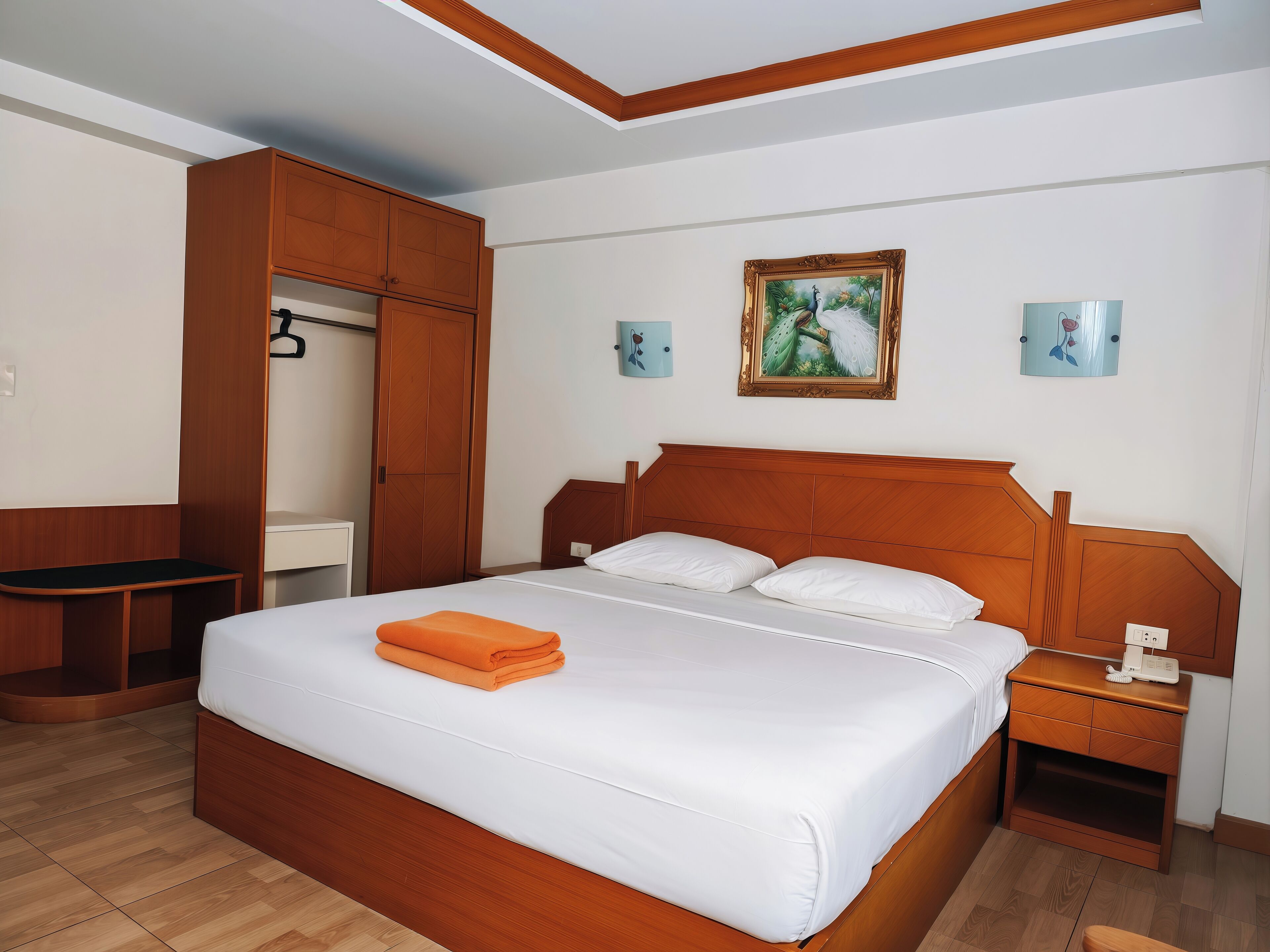 Un dormitorio ordenado con una cama de madera, un armario, una mesita de noche con una lámpara y un cuadro en la pared.