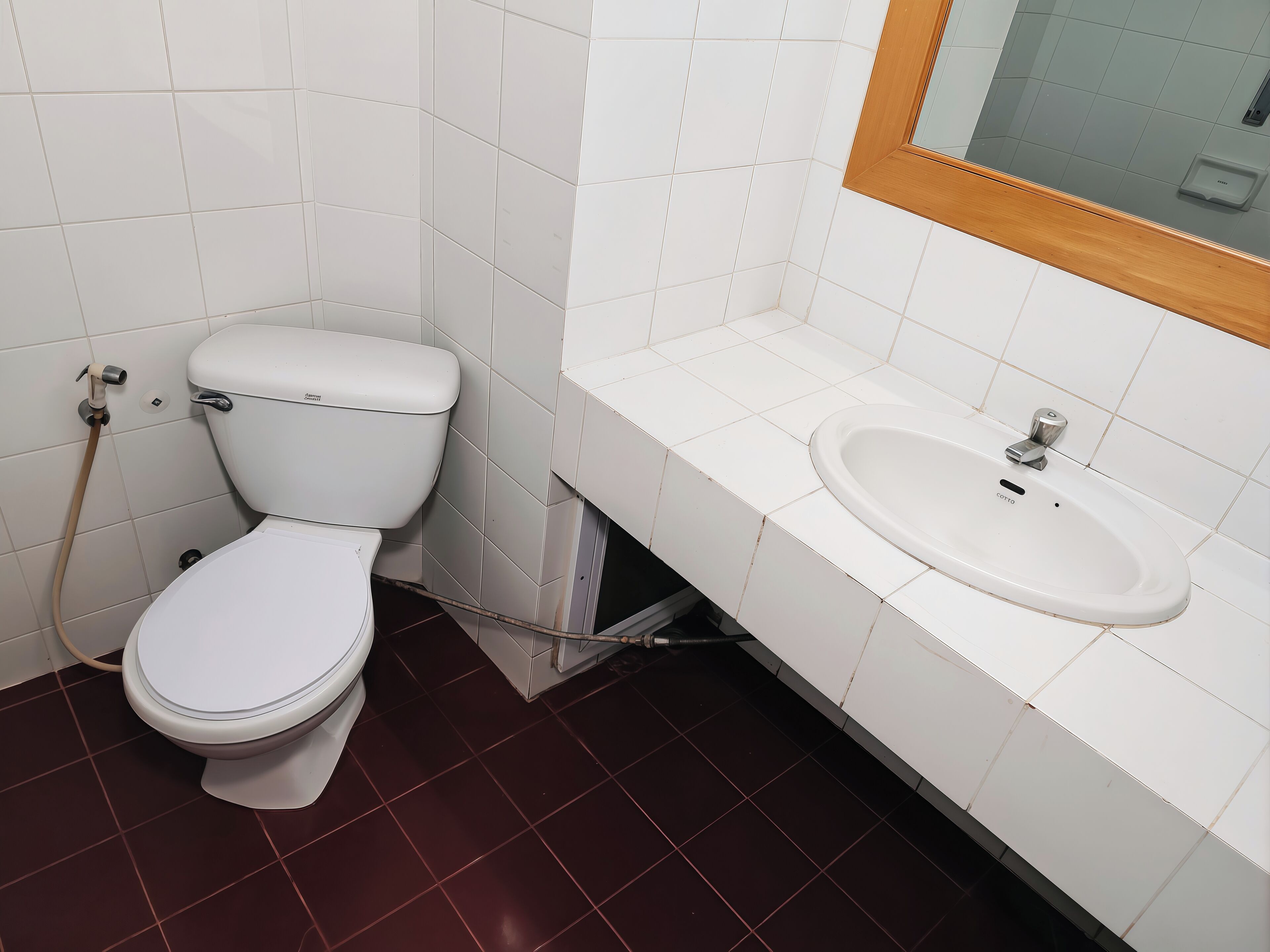 A bathroom with a toilet, sink, and mirror.