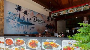 A restaurant with a mural of a tropical scene and a menu board displaying various dishes. - Dream Hotel Pattaya (Pattaya)
