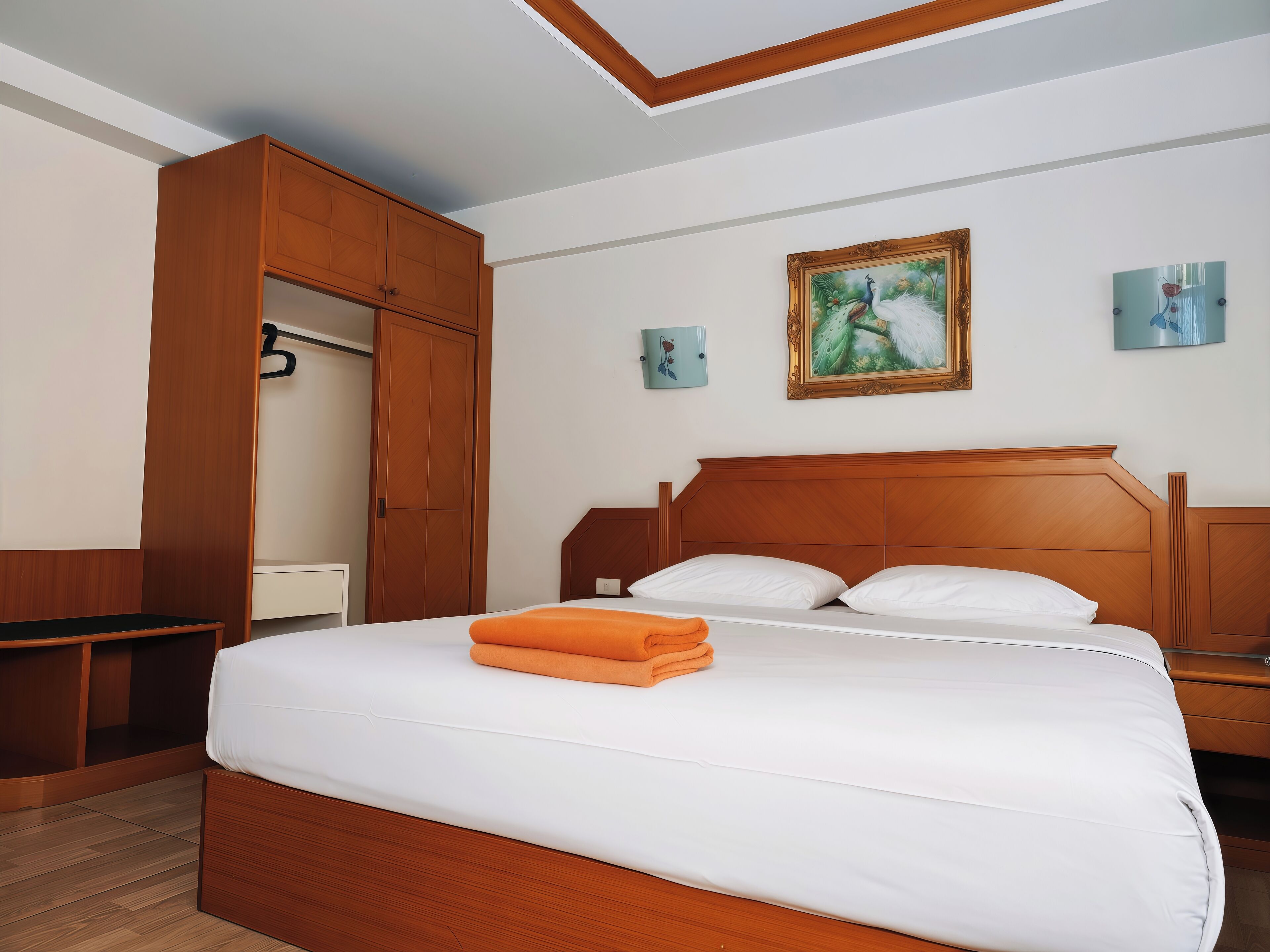 A hotel room with a wooden bed, a wardrobe, and a painting on the wall.