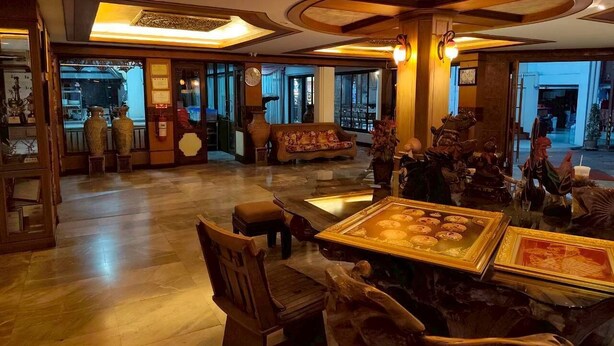 A lobby with a wooden floor, a sofa, a table with framed artwork, and a large window. - Dream Hotel Pattaya (Pattaya)