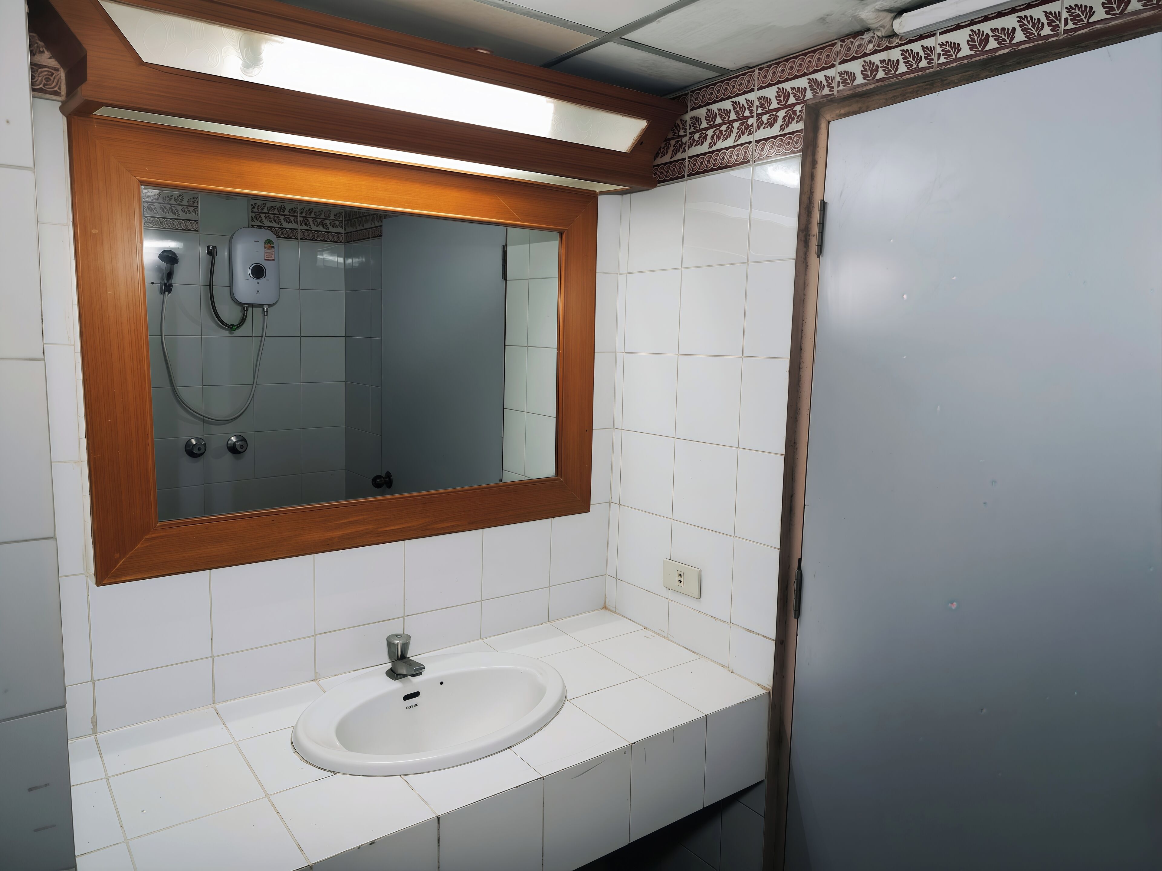 A bathroom with a wooden-framed mirror, a white sink, and a shower.