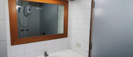 A bathroom with a wooden-framed mirror, a white sink, and a shower.