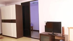 Una habitación con televisión sobre un mueble de madera, un armario y una puerta corredera que da a otra estancia.