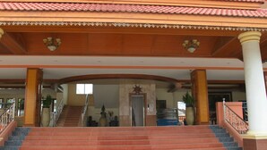 Un bâtiment doté d’un toit recouvert de tuiles, d’un escalier menant à l’entrée et d’une grande colonne.