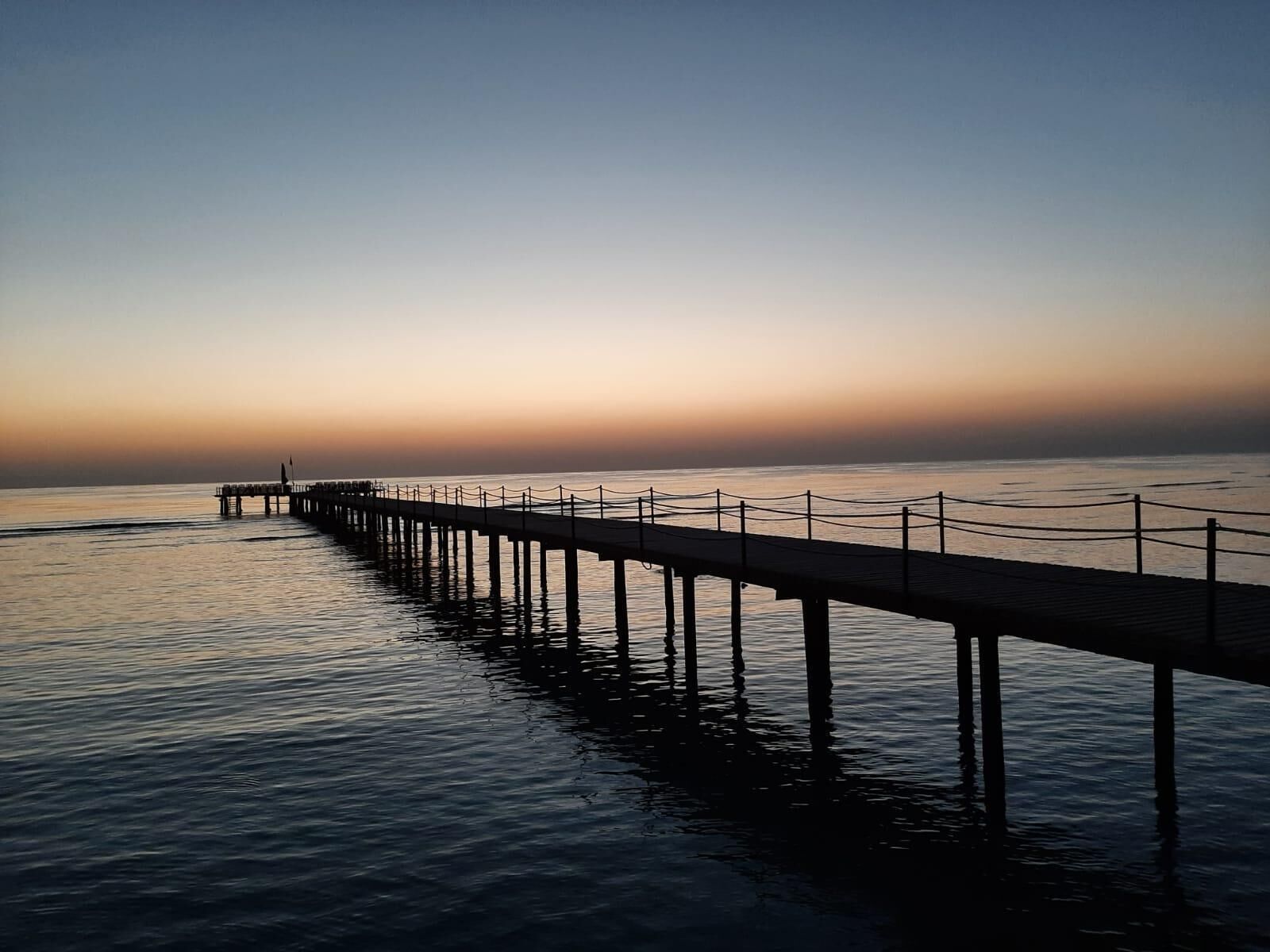 A pier extending into calm waters at sunset.