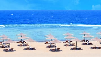 A beach with rows of sun loungers and thatched umbrellas.