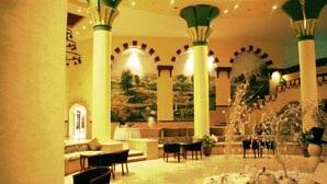 A lobby with high ceilings, columns, and a fountain. There are seating areas and a mural on the wall. - Bliss Nada Beach Resort (Marsa Alam)