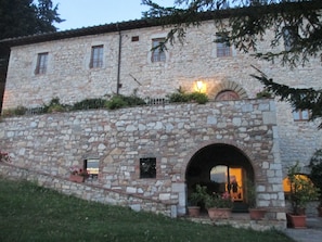 A stone building with a large arched entrance, potted plants, and a small balcony with railings. - Relais Villa Casalta (Castellina in Chianti)