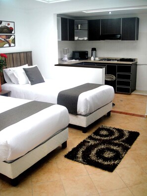 Une chambre avec deux lits, un coin cuisine et une salle de bain.
