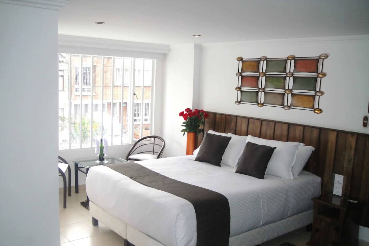 A neatly arranged bedroom with a bed, a chair, a small table, and a window.