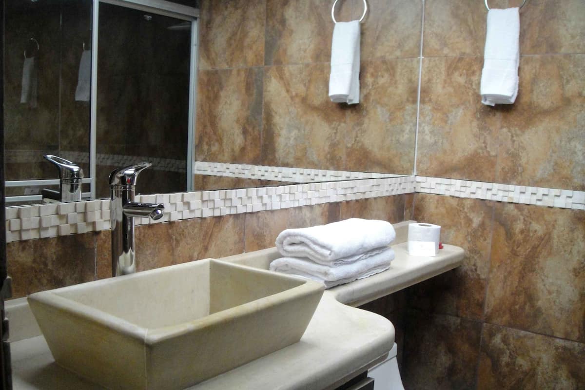 A bathroom with a beige sink, a mirror, a towel rack, and a toilet.