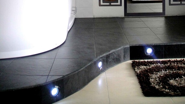 A modern bathroom with a large bathtub, a mirror, and decorative wall panels.