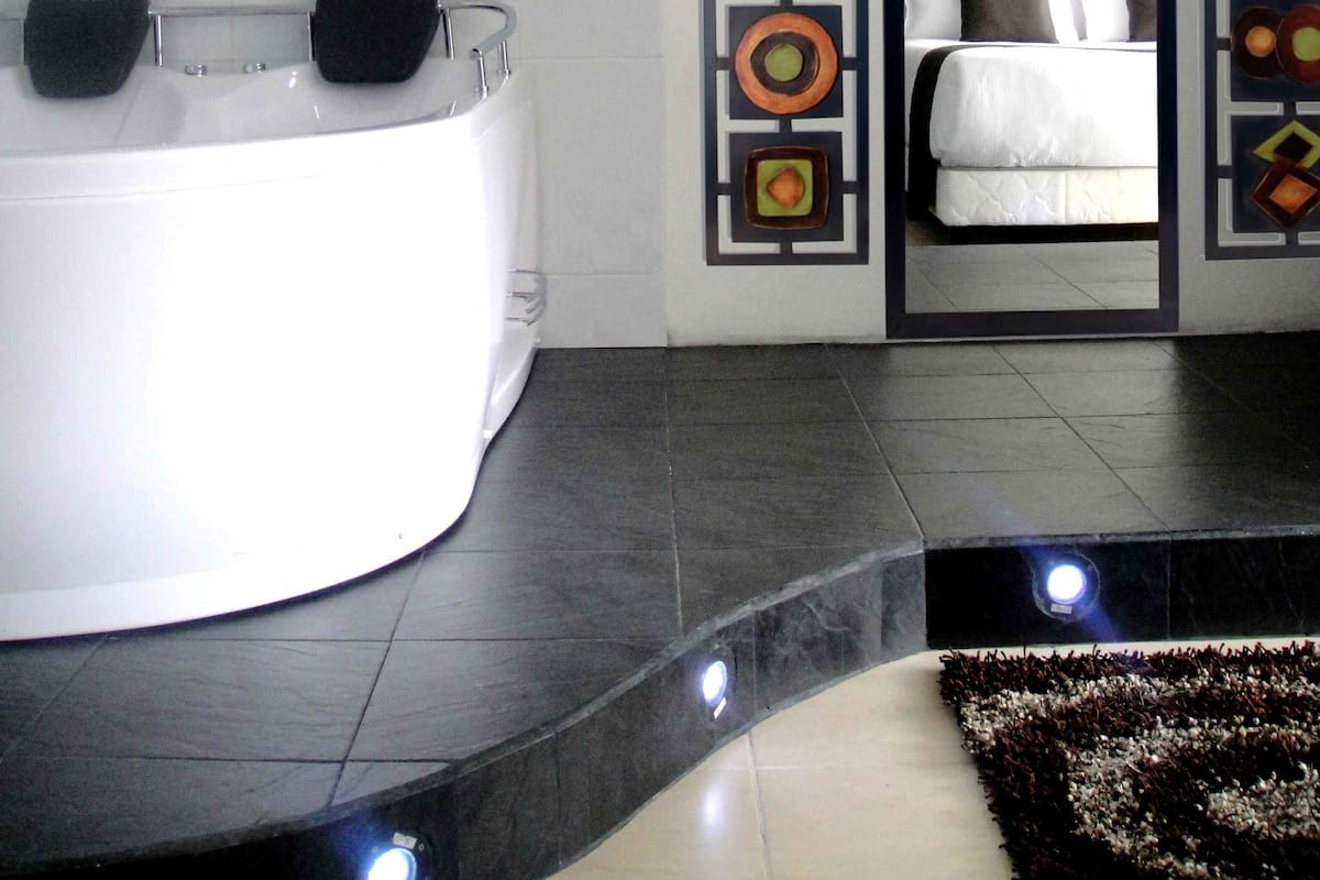 A modern bathroom with a large bathtub, a mirror, and decorative wall panels.