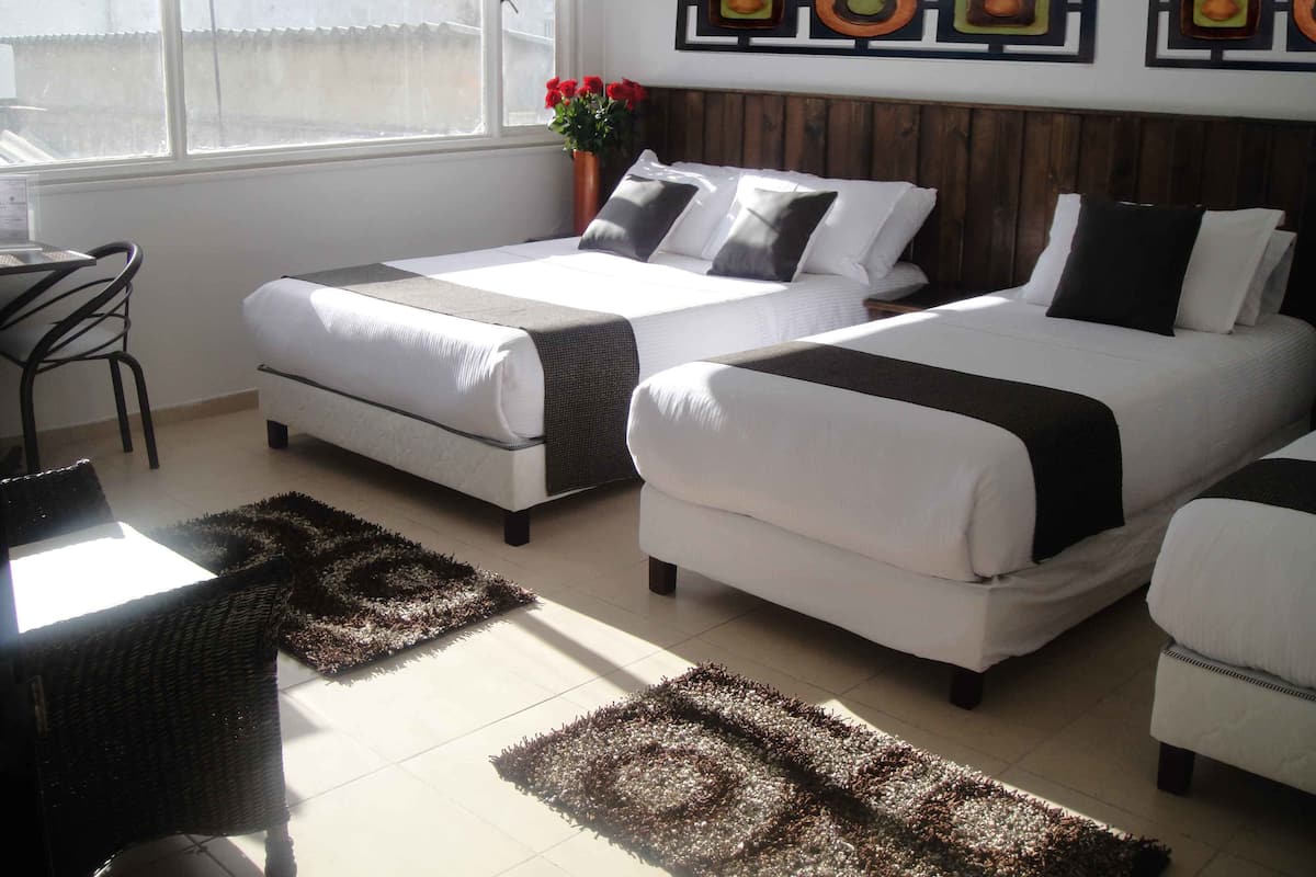 A hotel room with two beds, a dining table, and a chair.