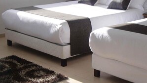 A bedroom with a bed, a bedside table, a chair, a window, and a vase with flowers.