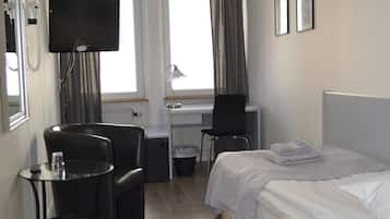 Une chambre d’hôtel équipée d’un lit, d’un bureau, d’une chaise, d’une télévision et d’une fenêtre avec des rideaux.