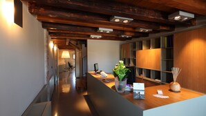 Un comptoir d’accueil avec un revêtement en bois, une plante en pot et un vase contenant des branches.
