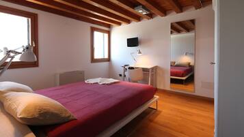 A bedroom with a bed, bedside lamps, a desk, and a mirror.