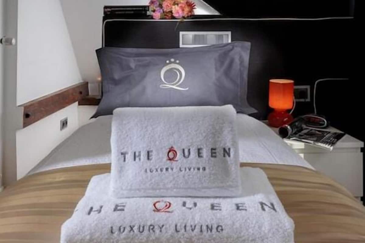 Ein ordentlich bezogenes Bett mit einem gefalteten Handtuch und einem Kissen mit einem Monogramm.