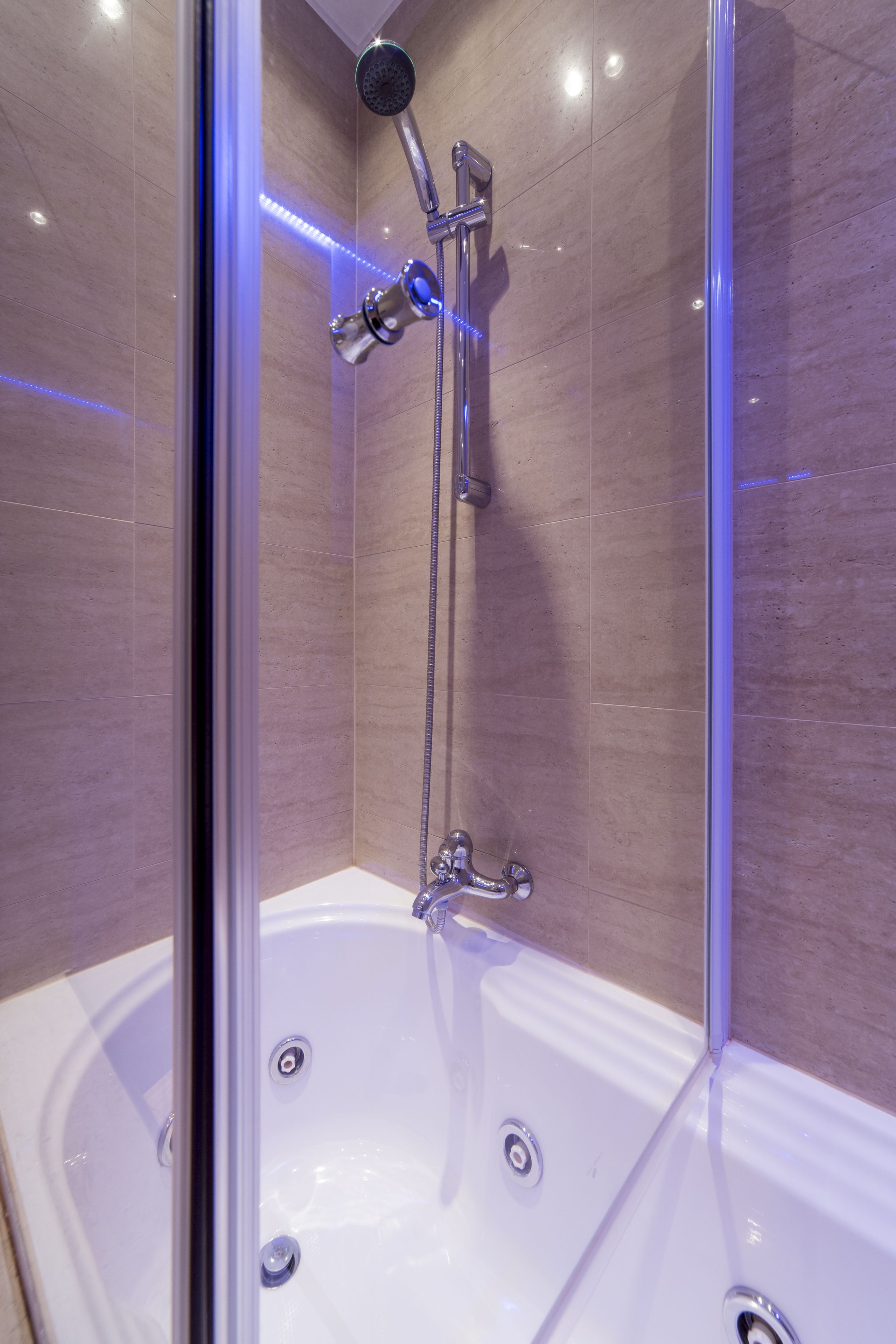 A modern bathroom with a glass-enclosed shower, a white bathtub, and a chrome showerhead.