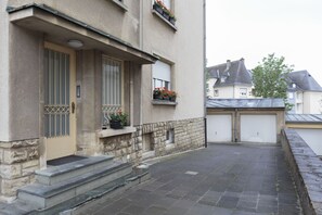 Een woongebouw met een gevel van natuursteen, een voordeur met een metalen hekwerk, een klein portaal met treden en een garage.