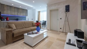 Una sala moderna con un sofá, una mesa de centro con un jarrón y una consola blanca con un control remoto.