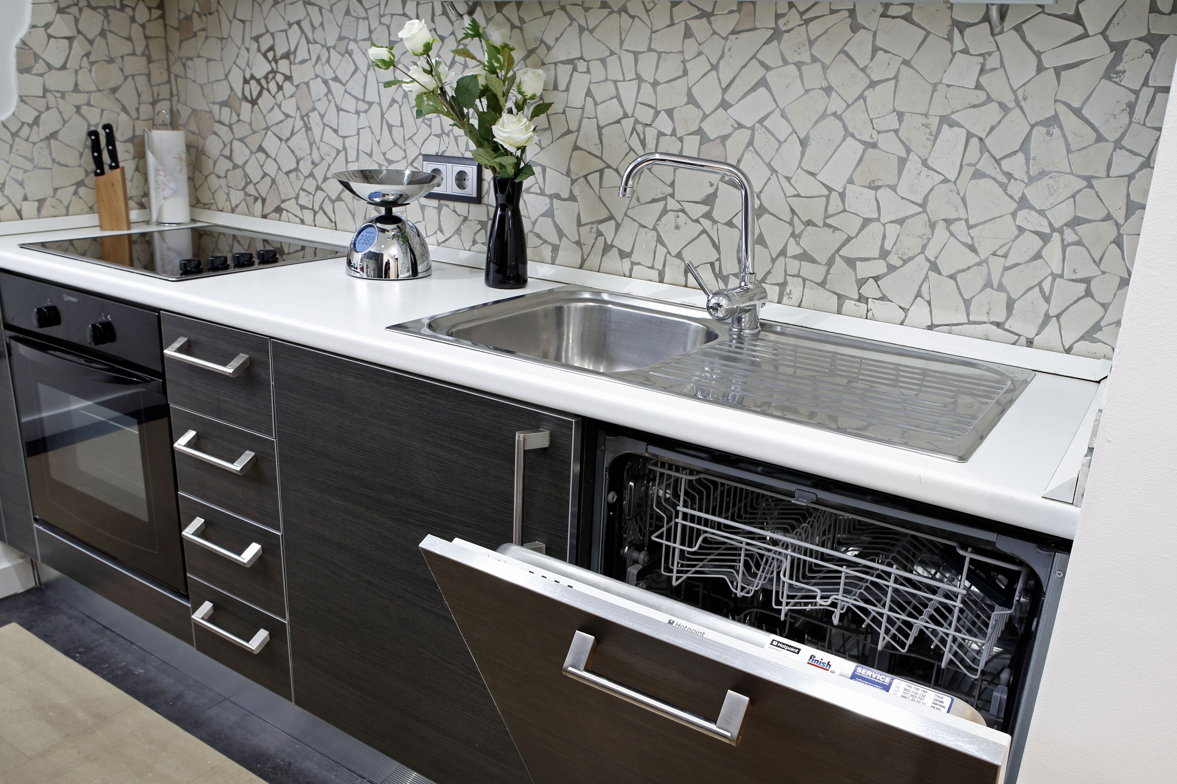 A modern kitchen with a stainless steel sink, a dishwasher, and a tiled backsplash.